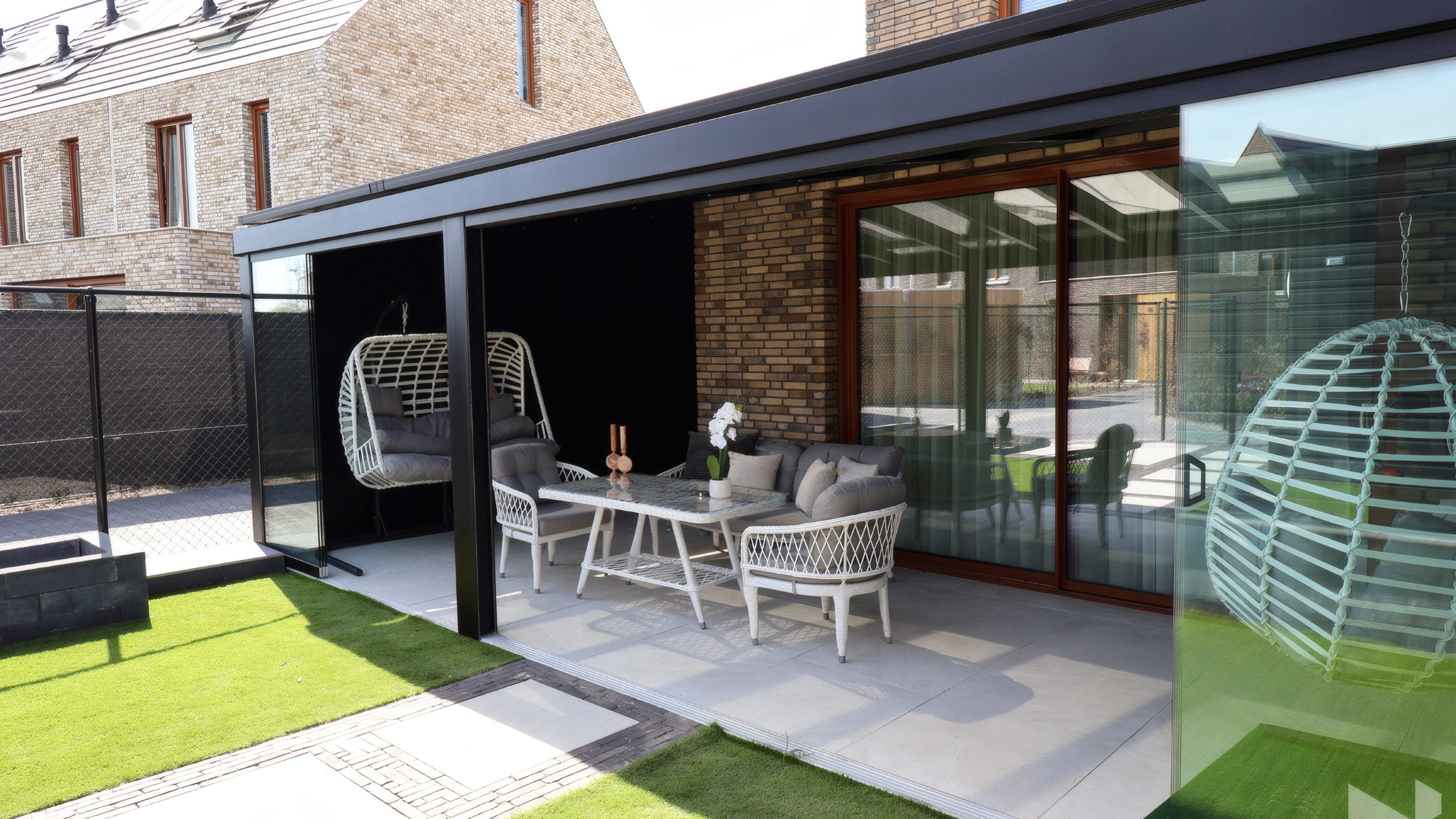 MB Solid Terrassendach mit rahmenlosen Glasschiebewänden an einem Klinkerhaus